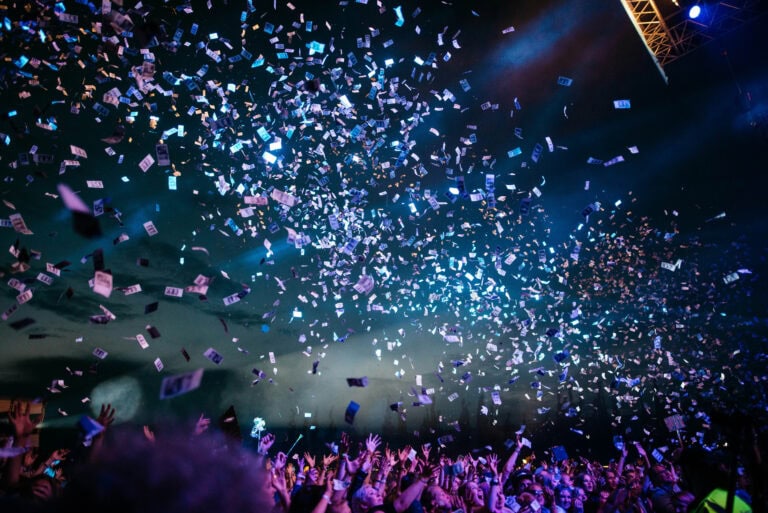 Confetti falling over excited crowd at concert or event, vibrant and lively atmosphere.
