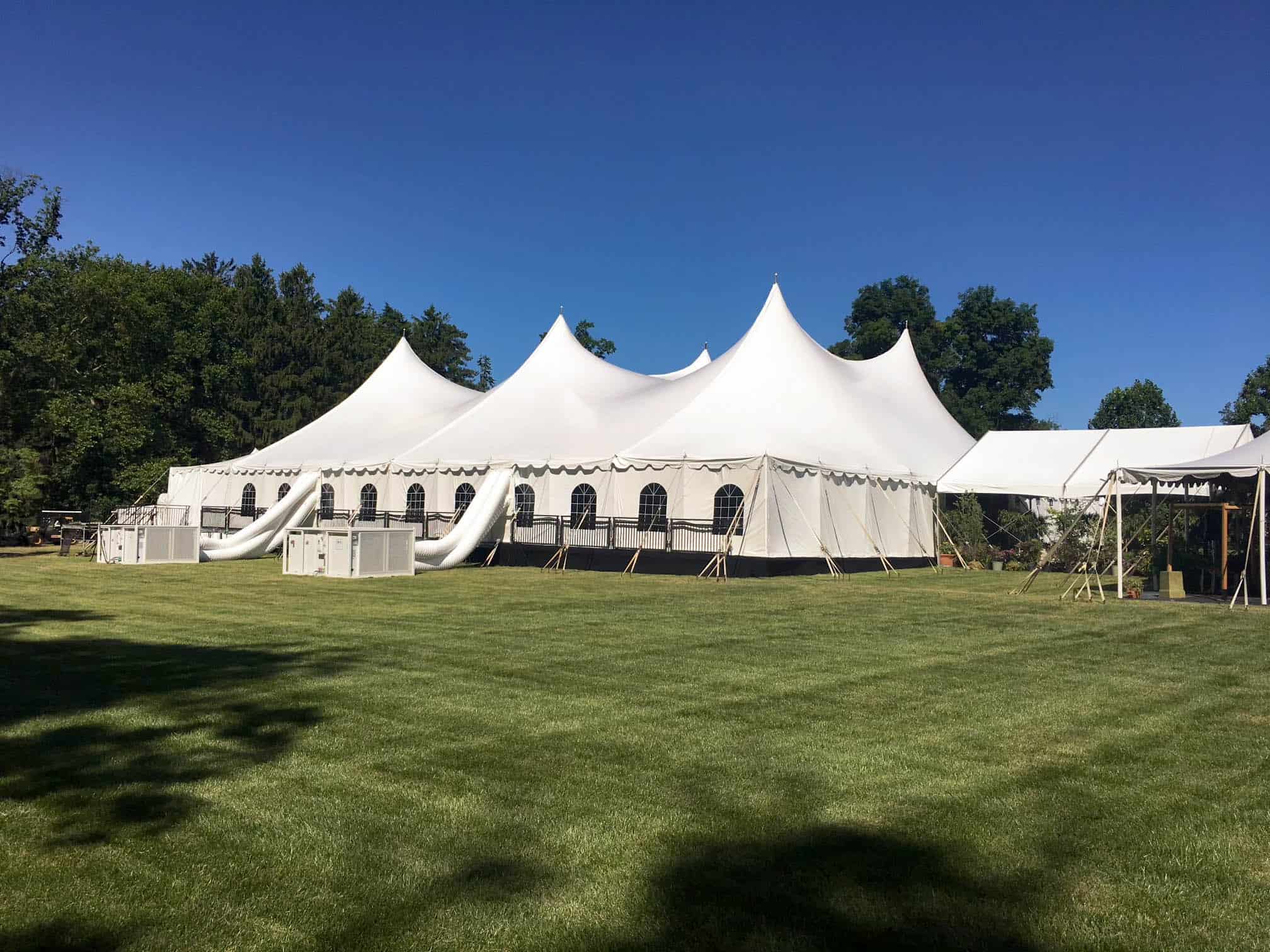 Large white event tent with slides on a grassy field, ideal for rentals and outdoor gatherings.