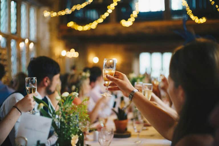 Elegant wedding celebration with guests toasting champagne in a rustic, decorated venue.