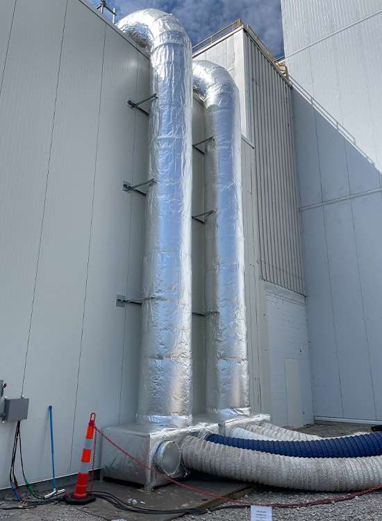 Heavy industrial ventilation ducts on commercial building exterior.