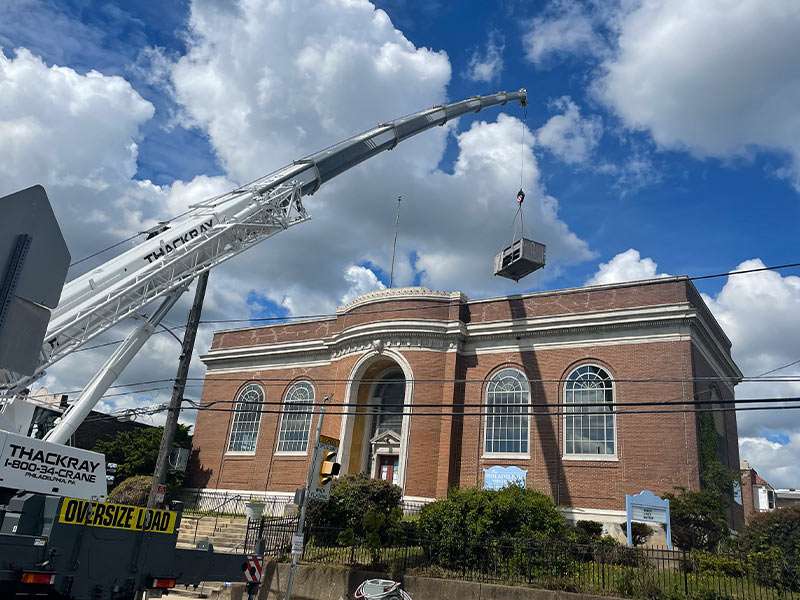 Crane lifting building equipment during renovations at historic REIC rental property.