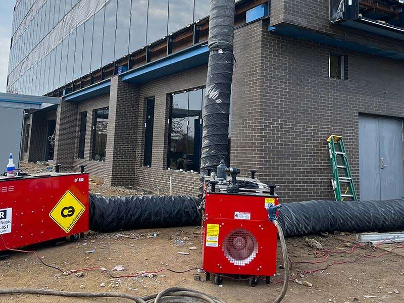Modern commercial building under construction with HVAC equipment and construction tools.