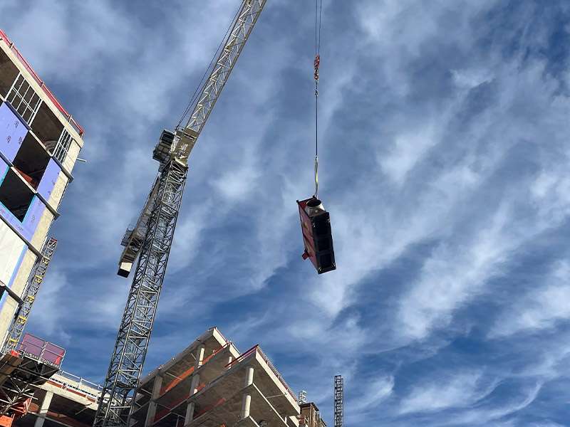 Construction crane lifting a modular unit at a commercial building site, showcasing industrial real estate development.