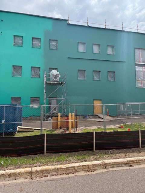 Large teal building under construction, REIC Rentals property development site, urban construction project.