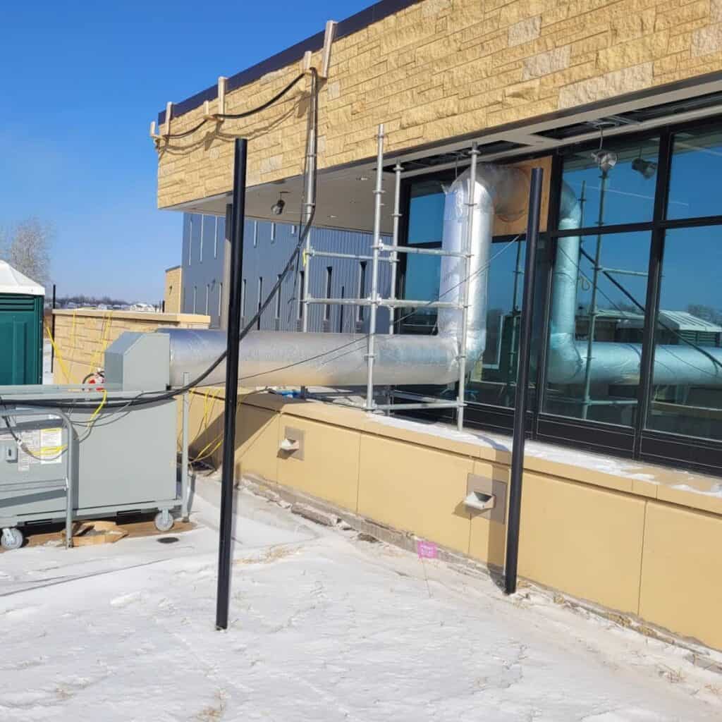 Scaffolding and HVAC system installation on a commercial building rooftop for REIC Rentals.