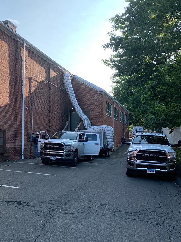 Industrial building with ventilation ducts and parked trucks for rent.