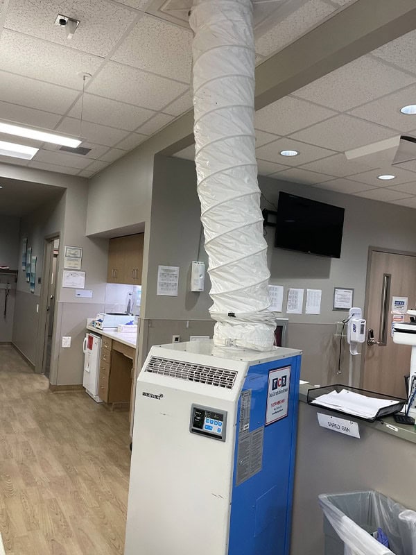 High-efficiency portable air scrubber in medical facility for enhanced air quality and infection control.