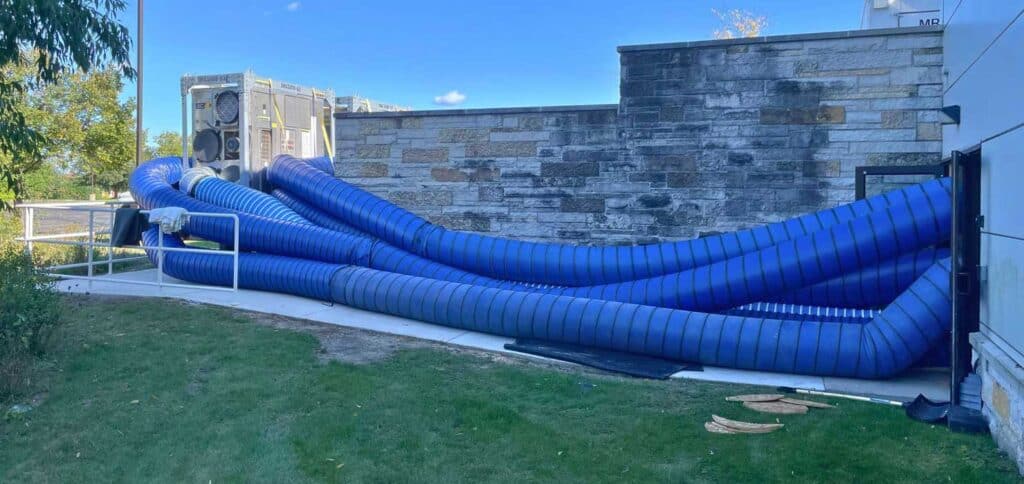 Large industrial cooling vent with blue flexible ducts at REIC Rentals property installation.