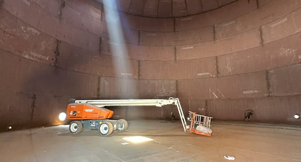 Indoor industrial space with a cherry picker lift and sunlight streaming through an opening.