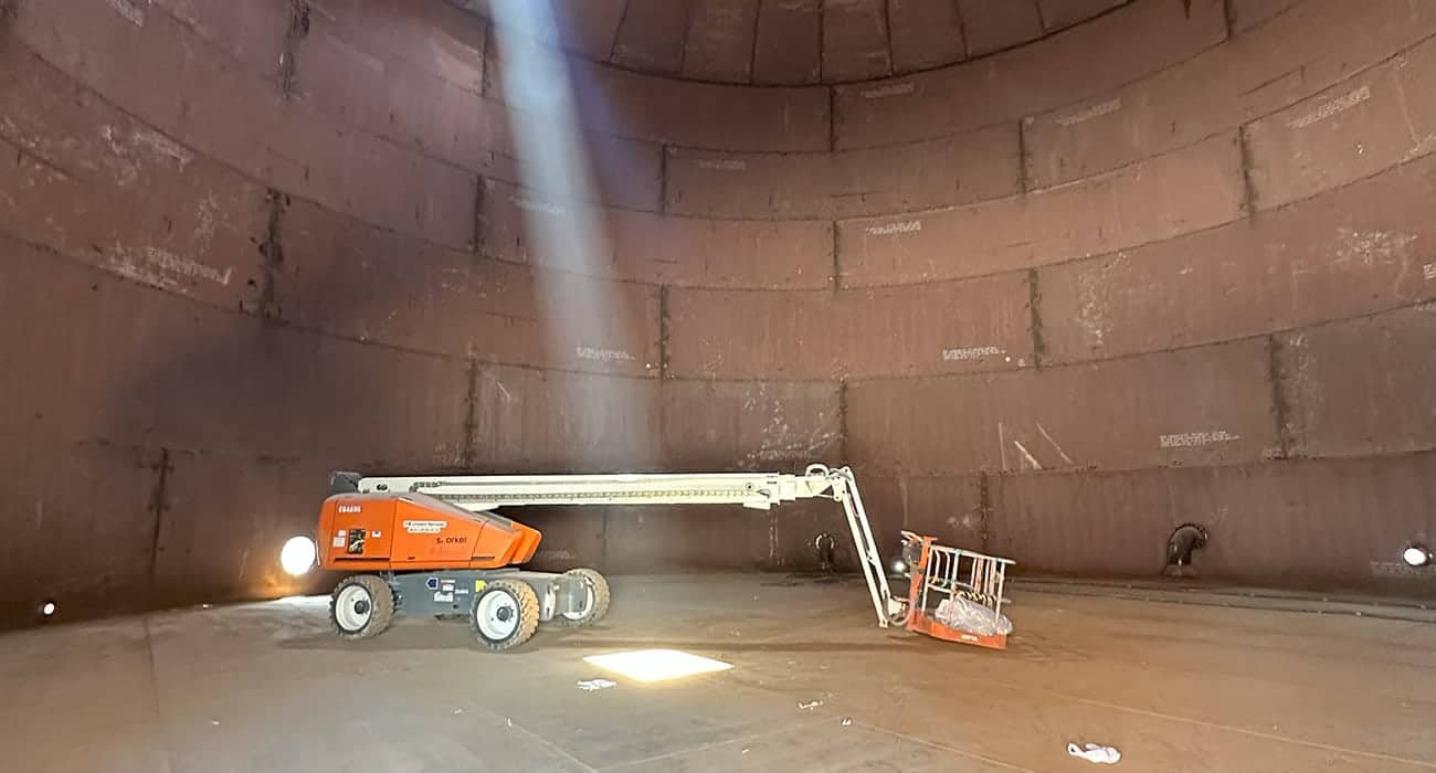 Indoor industrial space with a cherry picker lift and sunlight streaming through an opening.