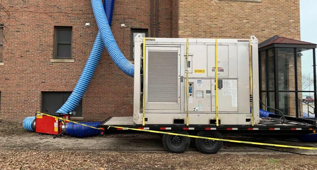 Large industrial HVAC unit with blue exhaust ducts outside of commercial building.