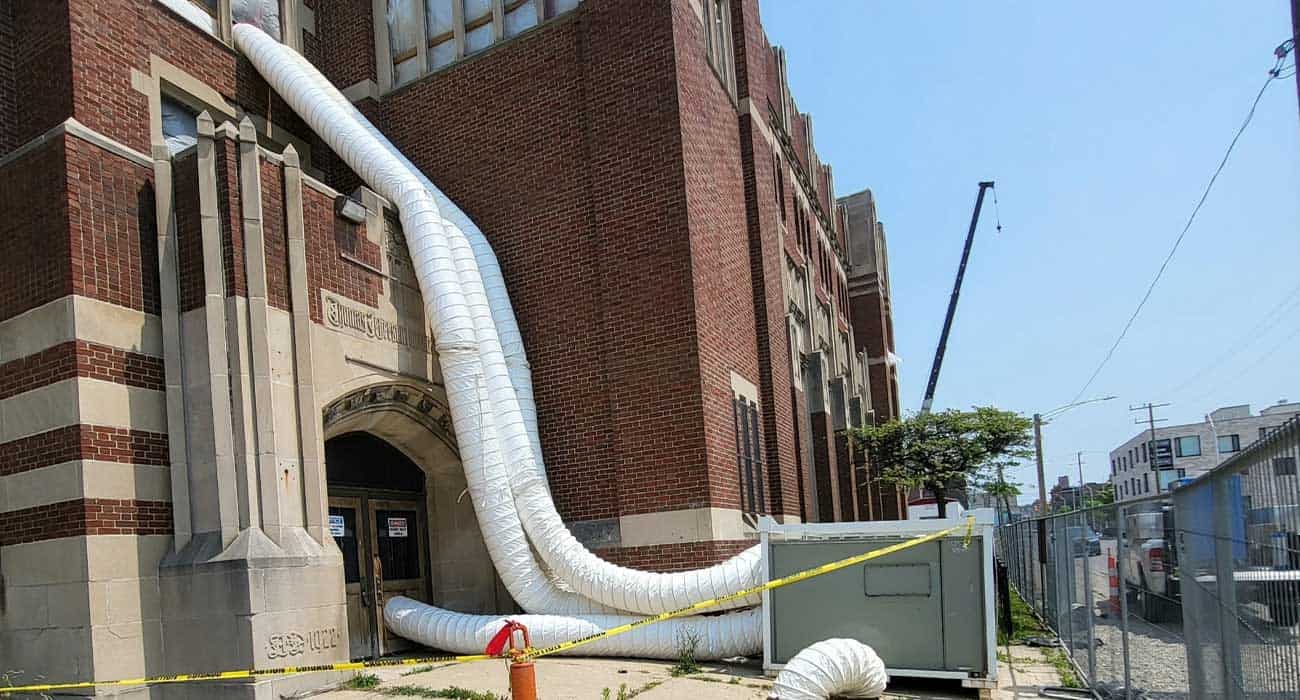 Large HVAC duct installation outside brick building for commercial property rental.