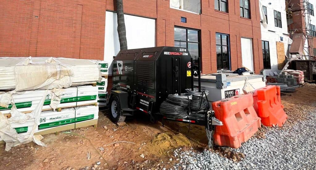 Construction site with REIC Rentals equipment and building materials.