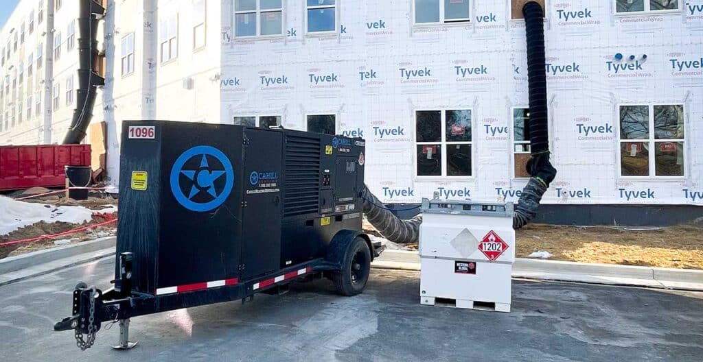 Portable generator on construction site with building under renovation in the background.