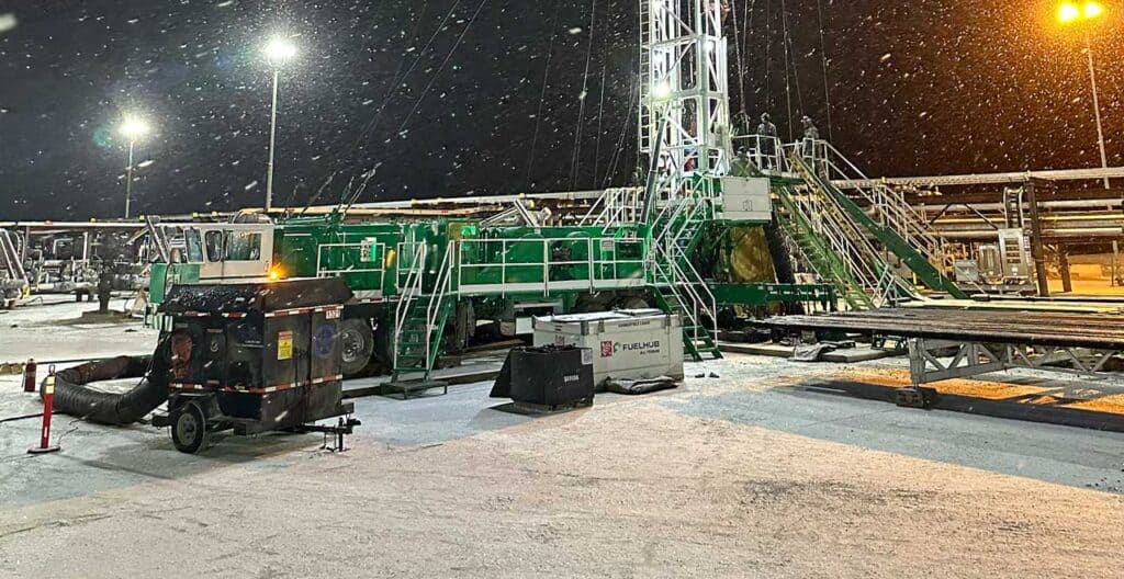 Heavy-duty oilfield drilling rig equipment at night, snow, cold weather, industrial setup, REIC Rentals Rentals.