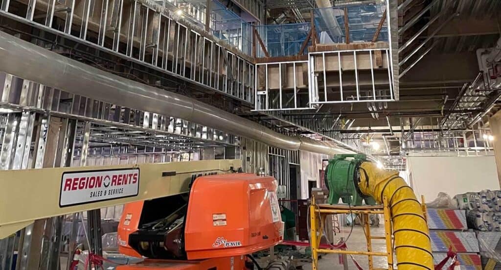 Industrial construction site with framing, ductwork, and equipment for commercial building project.