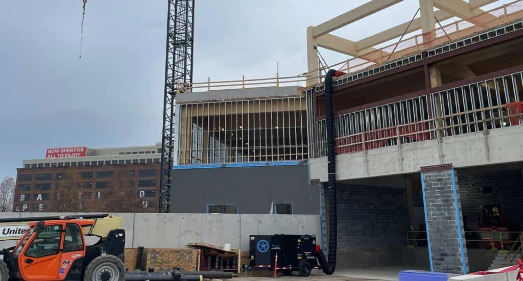 Construction of new apartment building on a busy urban street, showcasing ongoing development and modern architecture.