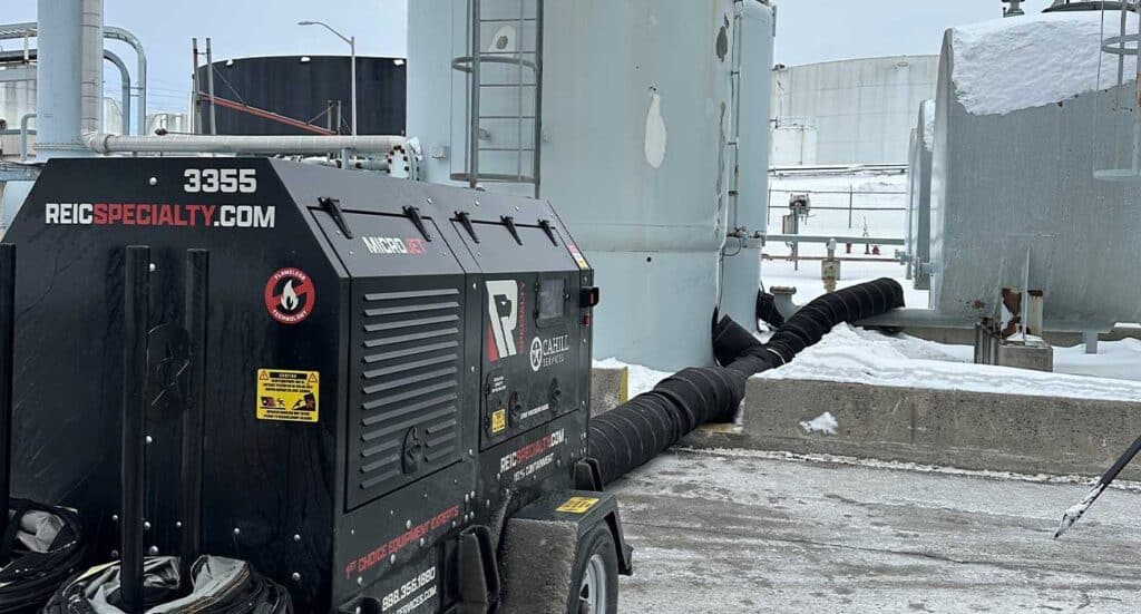 High-capacity industrial generator on rooftop with snow, HVAC systems, and cityscape background.