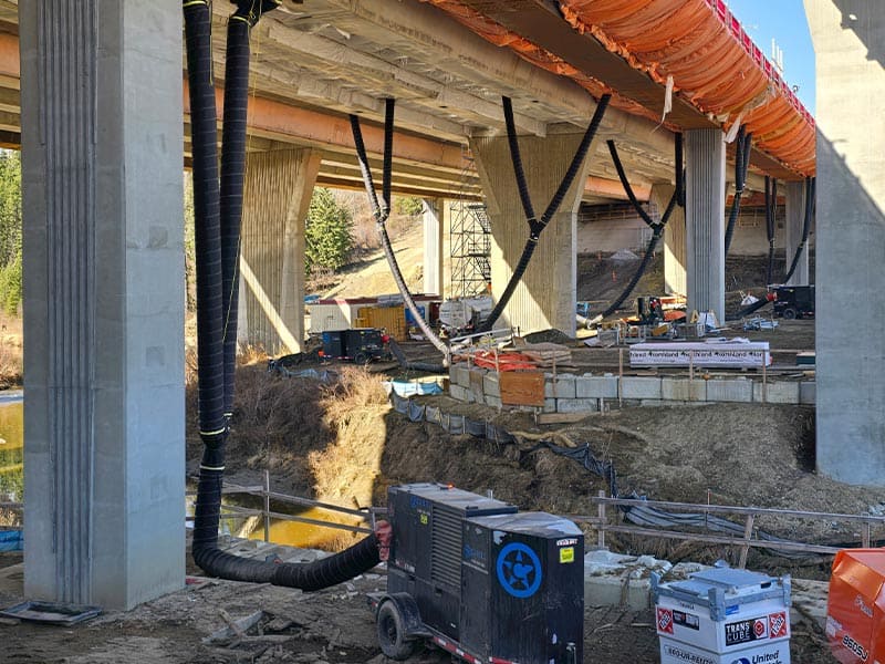 Construction site under a bridge with ongoing building work and equipment.