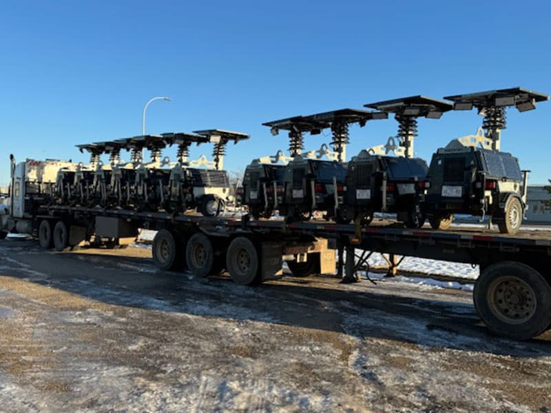 Heavy-duty military vehicles on flatbed truck at a single location.