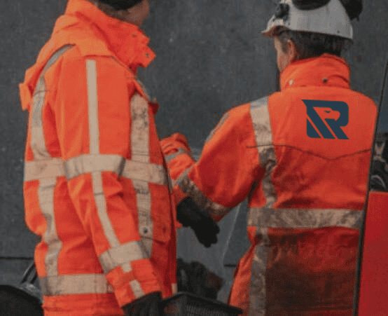 High-visibility construction workers in orange safety gear collaborating outdoors.