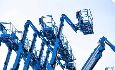 Blue aerial lifts and cherry pickers at a construction site.