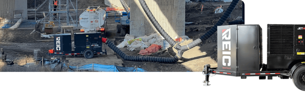 Heavy-duty construction site with REIC Rentals equipment and ventilation hoses for building projects.