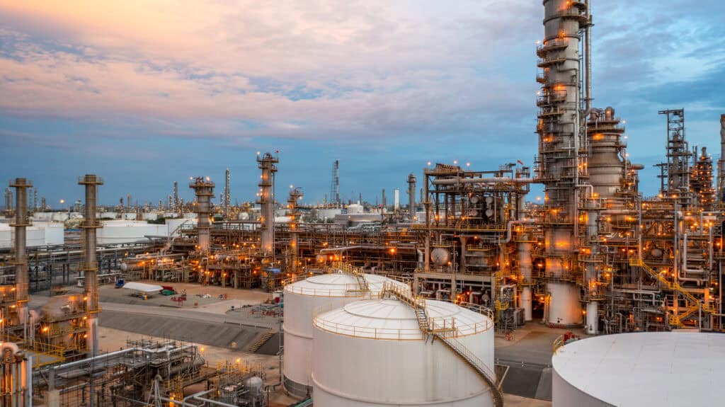Oil refinery industrial plant at dusk with tanks and pipelines for commercial real estate and industrial property SEO.