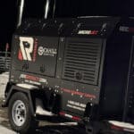 REIC Rentals portable generator for construction site power supply at night.