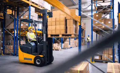 Forklift moving boxes in warehouse storage facility for rental logistics solutions.