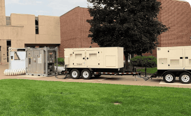 Portable generator units and electrical equipment outside a building on a trailer.