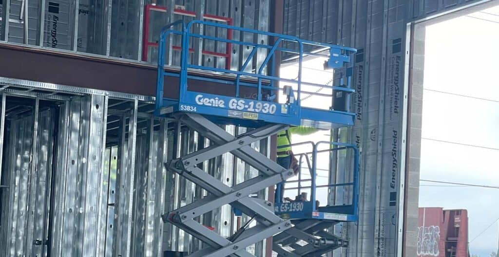 Scissor lift working on building during winter conditions at REIC Rentals.