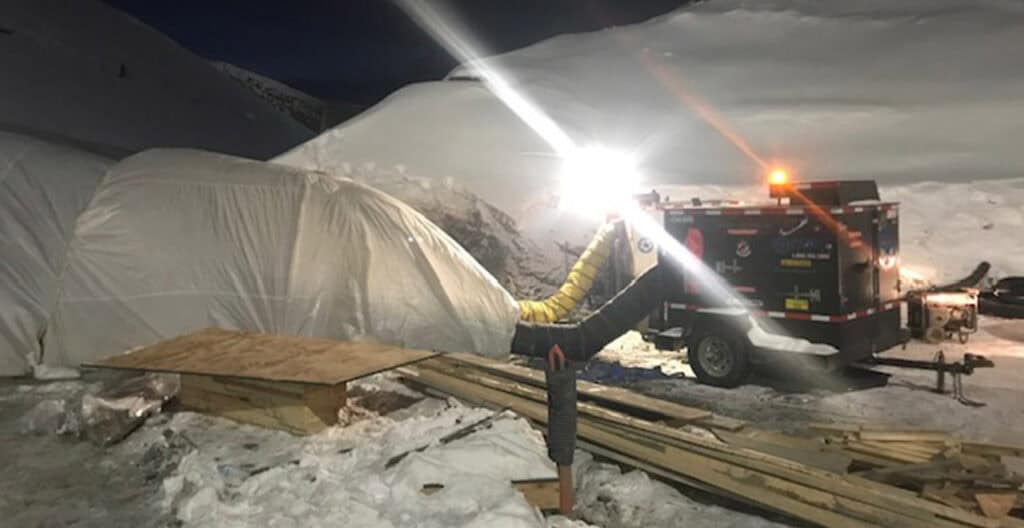 Portable heater used for winter construction heating in snowy outdoor environment.