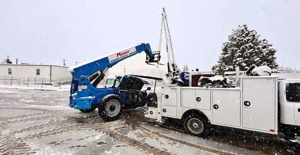 Mobile crane and utility truck with snow removal equipment in winter conditions.
