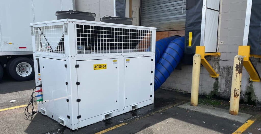 Industrial cooling unit with ventilation duct outside a building.