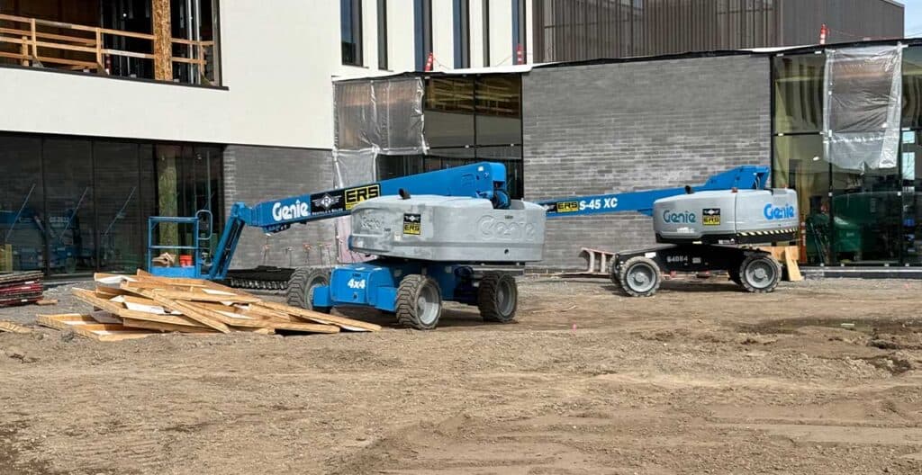 Construction site with Genie boom lifts during peak season equipment rental.