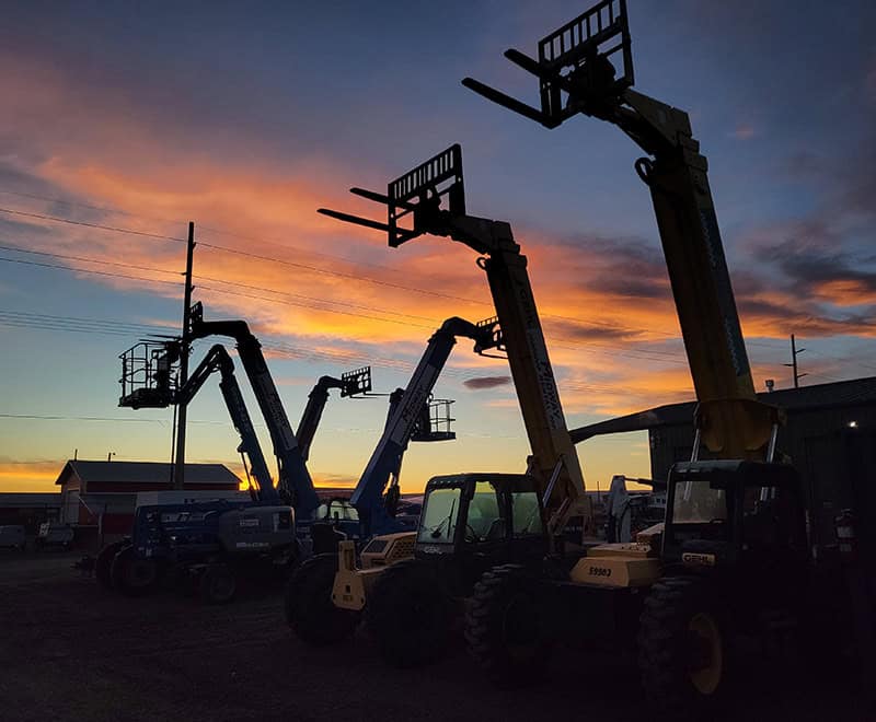 Lift trucks and construction machinery at sunset, ready for rental.