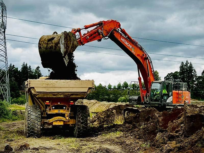 Excavator loading dirt into a dump truck on a construction site in Camas/Vancouver WA.
