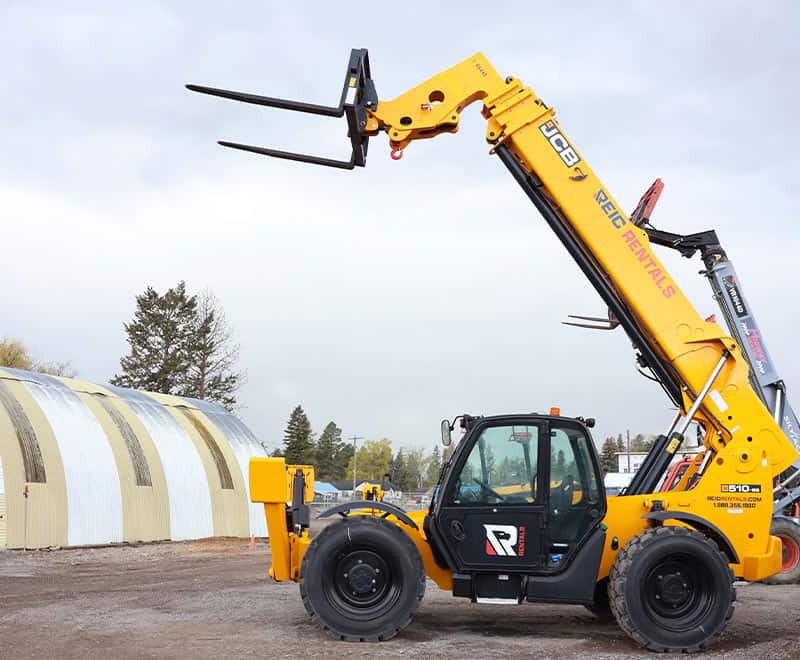 Yellow telehandler forklift with "REIC Rentals" branding on a construction site.