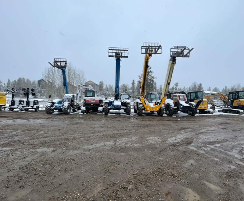 Heavy equipment and aerial lifts at REIC Rentals yard during winter.