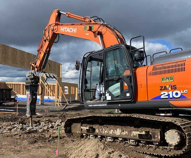 Excavator with orange body and black tracks working on a construction site.