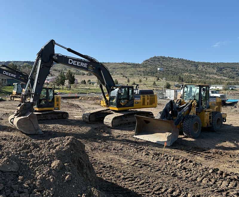Excavators and construction machinery on a dirt site, ready for rental or project use.