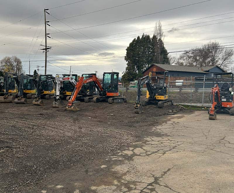 Construction mini excavators lined up at REIC Rentals yard for equipment rental services.