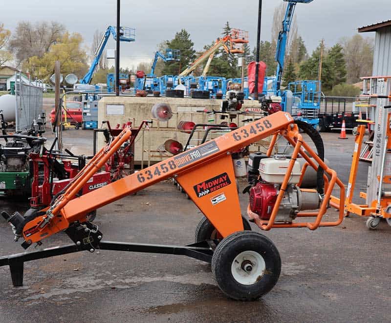Orange asphalt roller compactor with engine and wheels at construction site.