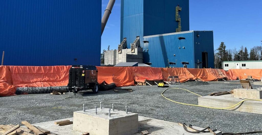 Industrial construction site with large blue storage tanks and equipment.