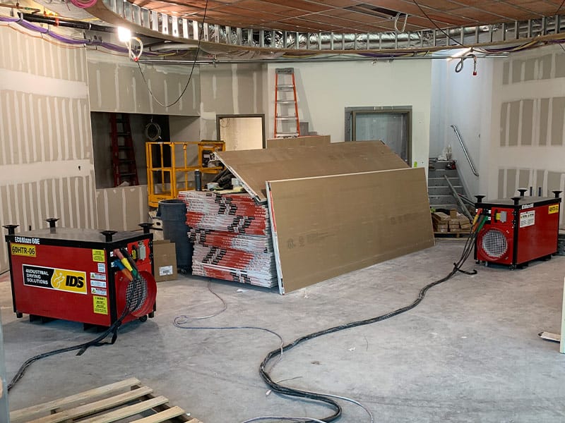 Construction site with drywall and equipment at REIC Rentals property.