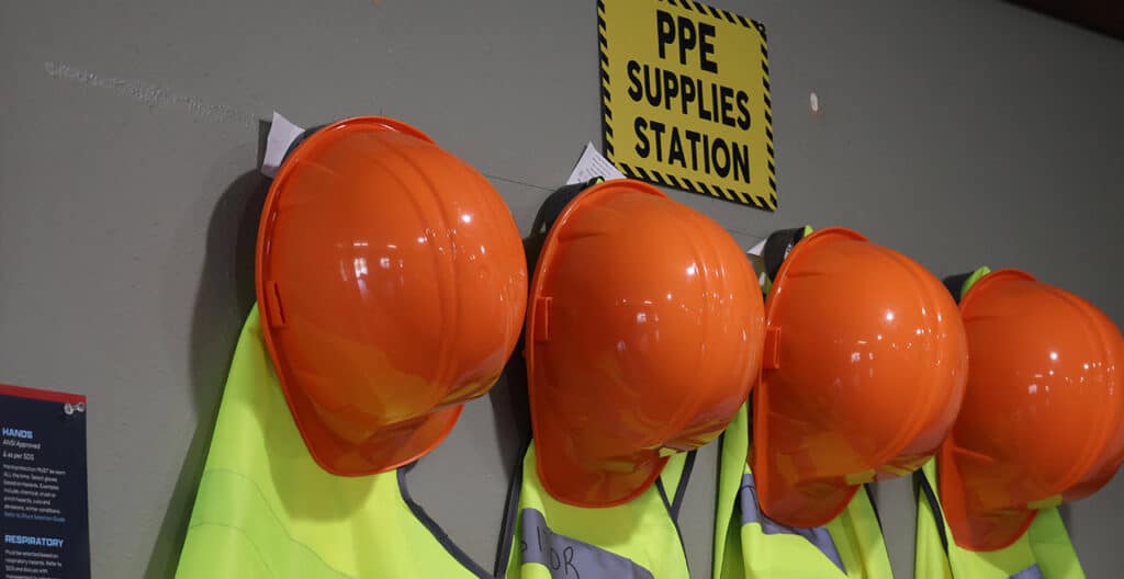 Safety helmets and vests stored at PPE supplies station.