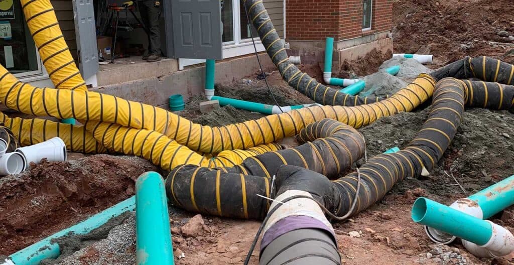 Installation of moisture barriers and drainage pipes at a construction site.