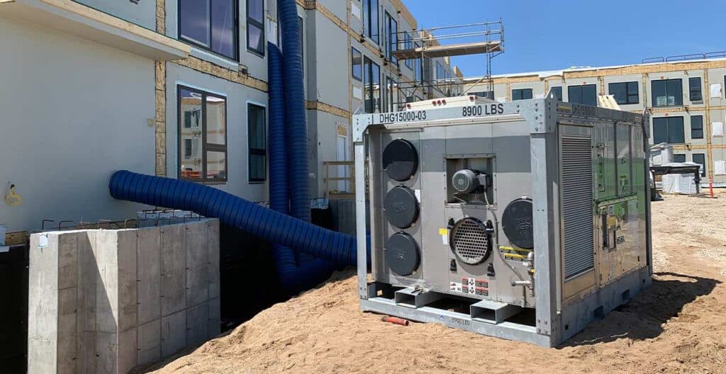 HVAC unit on a construction site with building framework in background.