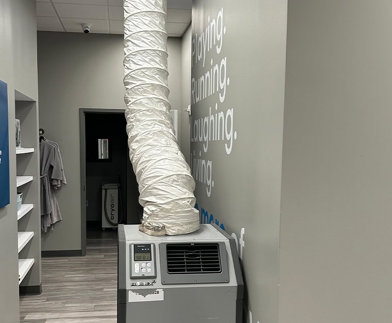 Portable air conditioning unit with exhaust hose in a modern office space.